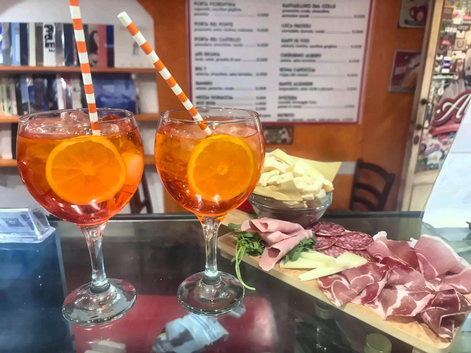 Due spritz con fetta d'arancia e un tagliere di salumi, formaggio e focaccia